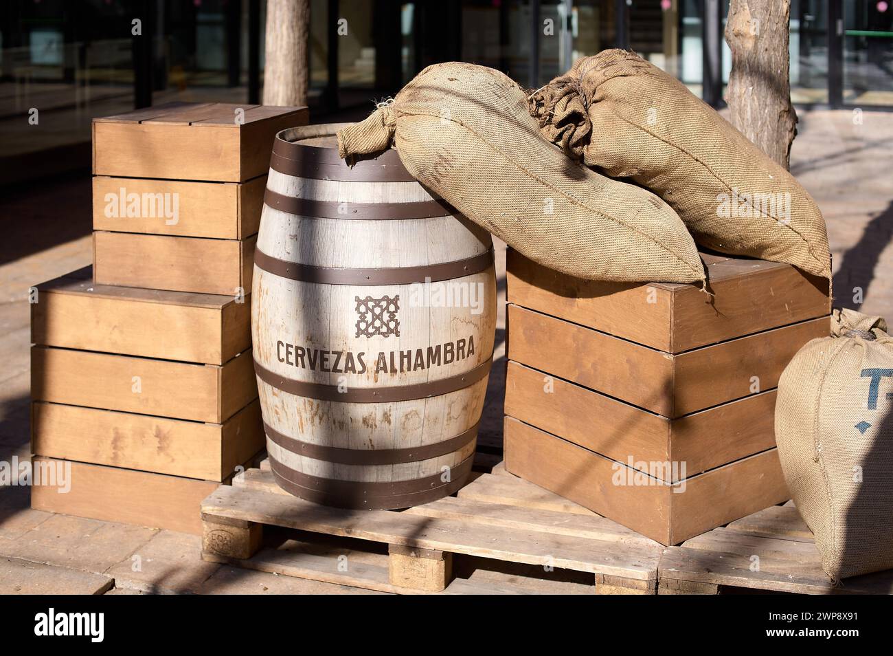 Barcelona, Spanien - 6. März 2024: Jutesäcke und ein Holzfass auf einer Palette, die an eine rustikale, traditionelle Szene erinnern, ideal für die Themen der Brauerei oder Stockfoto