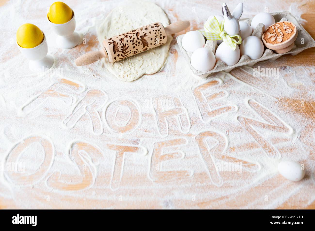 3. März 2024: Happy Easter Gruß geschrieben in Mehl neben Backutensilien, Eiern und Dekoration zu Ostern *** Frohe Ostern Gruß in Mehl schreibt neben Backutensilien, Eiern und Dekoration zu Ostern Stockfoto