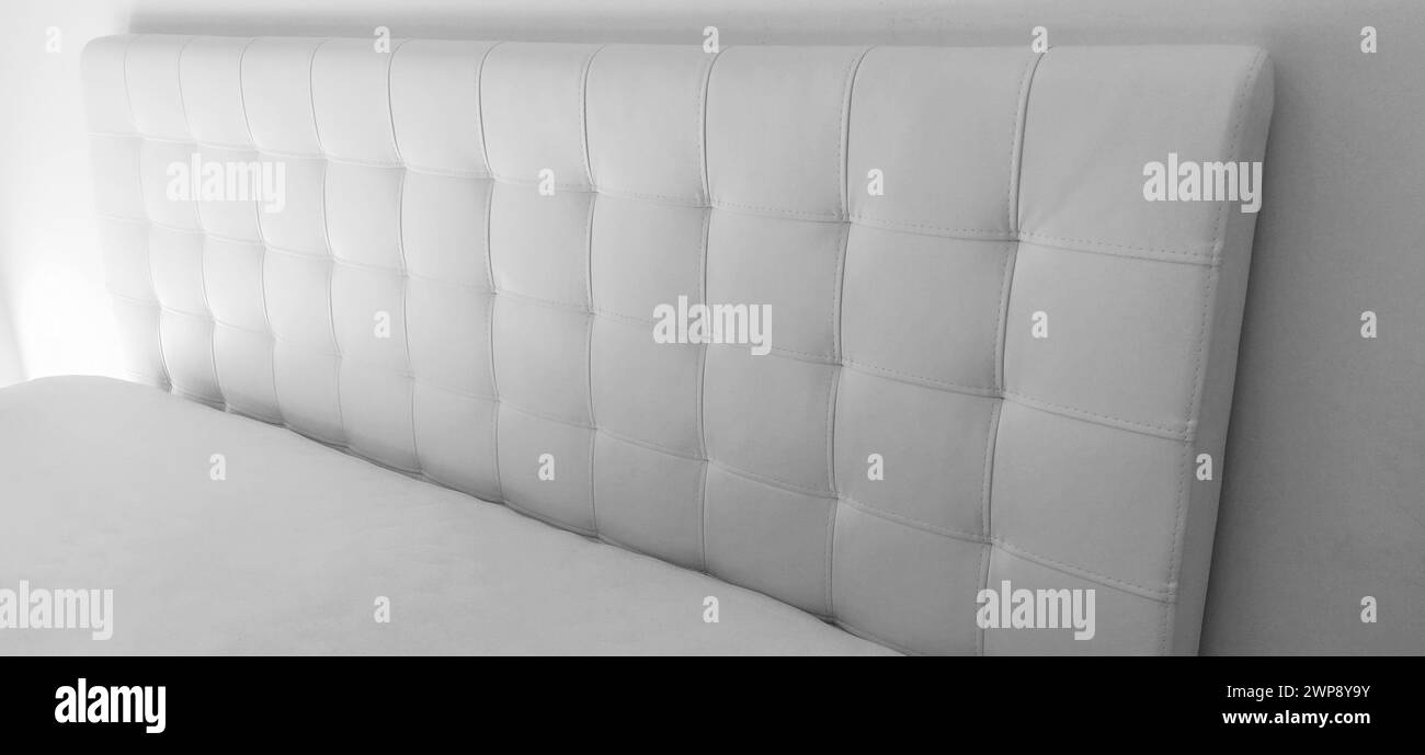 Weiches Kopfteil. Polster für Möbel aus echtem oder Kunstleder und gestepptem Stoff. Weiches Kopfteil gegen eine leichte Wand. Schwarz und Stockfoto