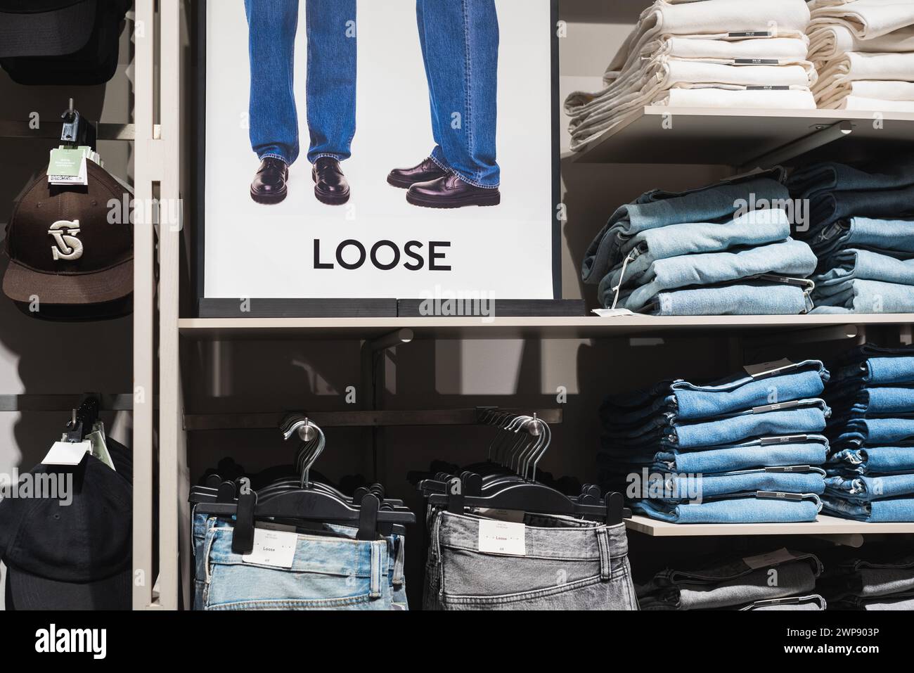 Lose Jeans auf Regalen und Poster, auf denen die losen Hosen im H&M Store am 3. März 2024 in Bangkok, Thailand, erklärt werden. Stockfoto