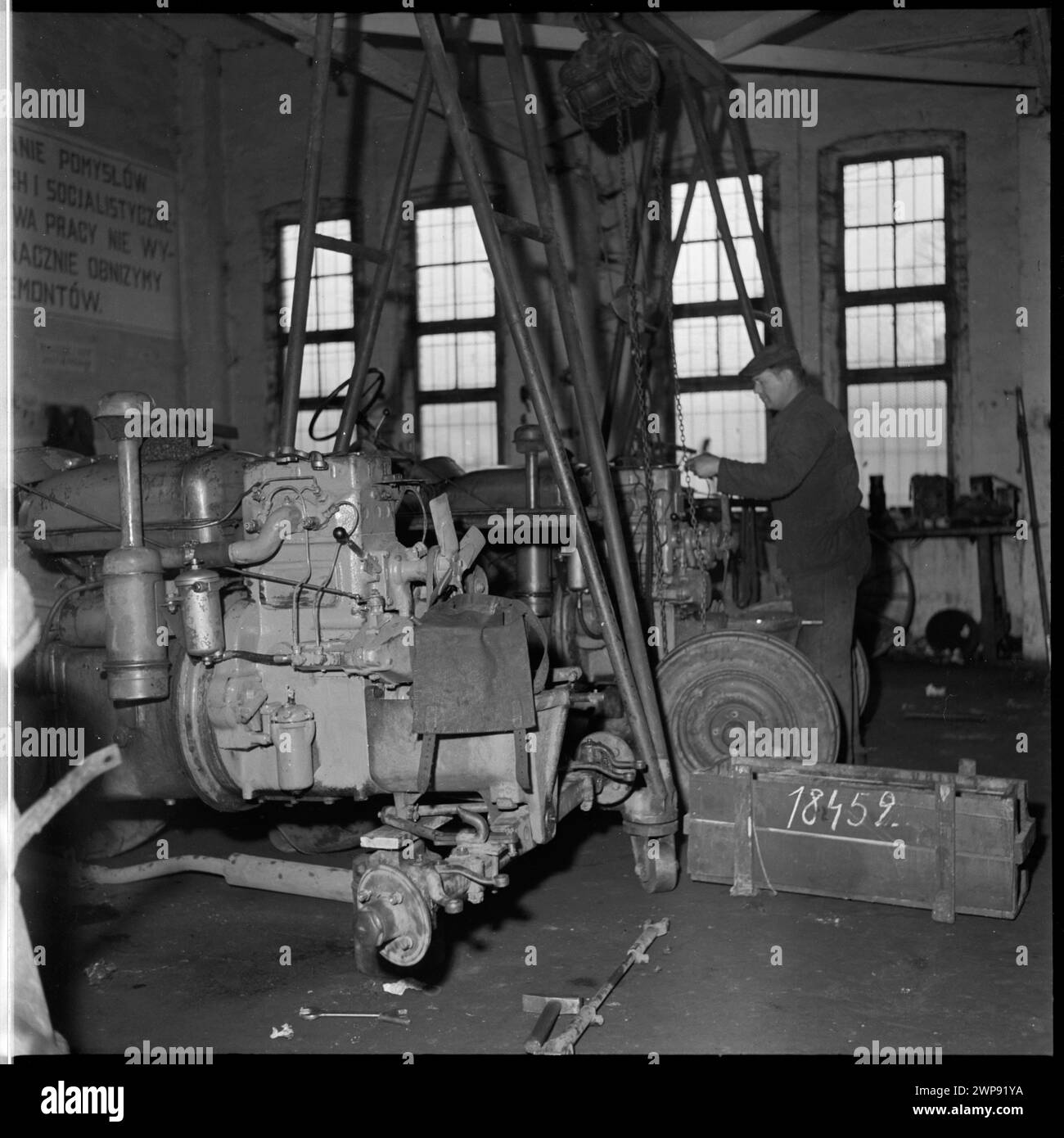 Foto eines Mechanikers, der 1954 landwirtschaftliche Maschinen in der PGR-Werkstatt in Karsk Pyrzycki repariert und instand hält, in Verbindung mit dem ersten Ursus-Traktor der Nachkriegszeit. Stockfoto