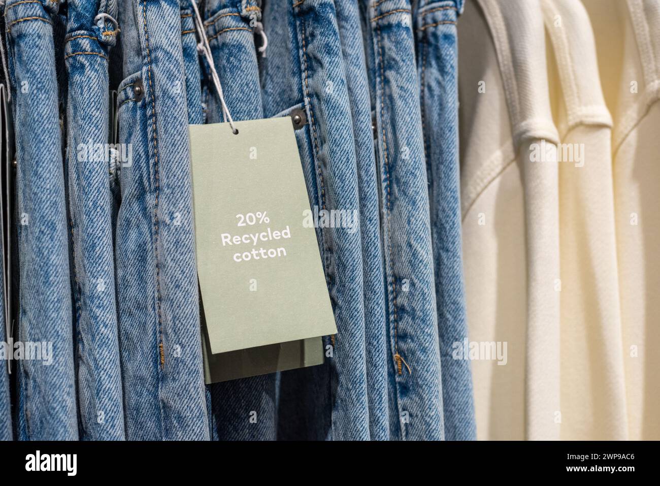 Umweltfreundliche Jeans mit einem Infoschild, das besagt, dass die Jeans aus 20 % recycelter Baumwolle hergestellt sind. Stockfoto