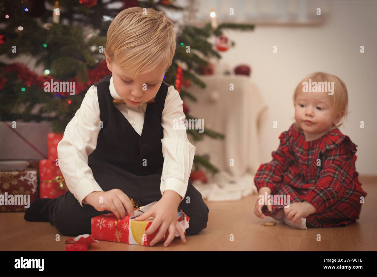 Kinder zum weihnachtsfeiertag packen Geschenke in der Nähe eines Baumes aus Stockfoto