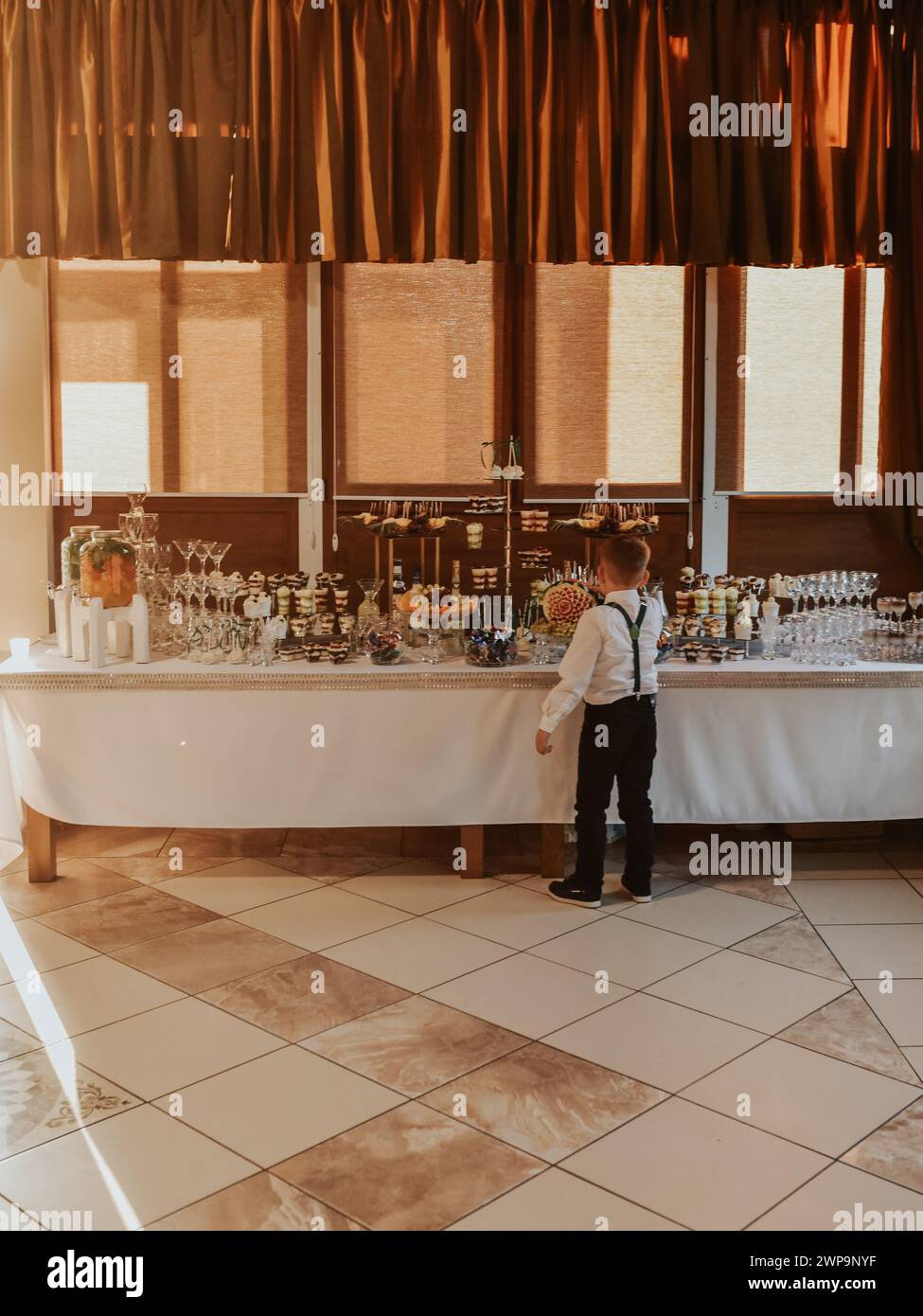 Boy Stand Essen in der Nähe Catering Hochzeitsbuffet für Veranstaltungen. Wunderschön dekoriertes Catering, Banketttisch, Snacks und Vorspeisen mit Sandwich Stockfoto