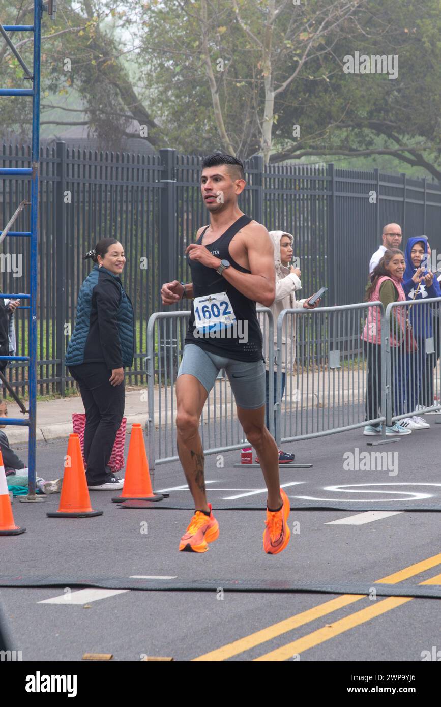 Der erste Läufer, Adrian Gudino, überquert die Ziellinie in der 18th Annual St. Patrick's Day 5 km Run & Walk, Pharr, Texas, USA. Stockfoto