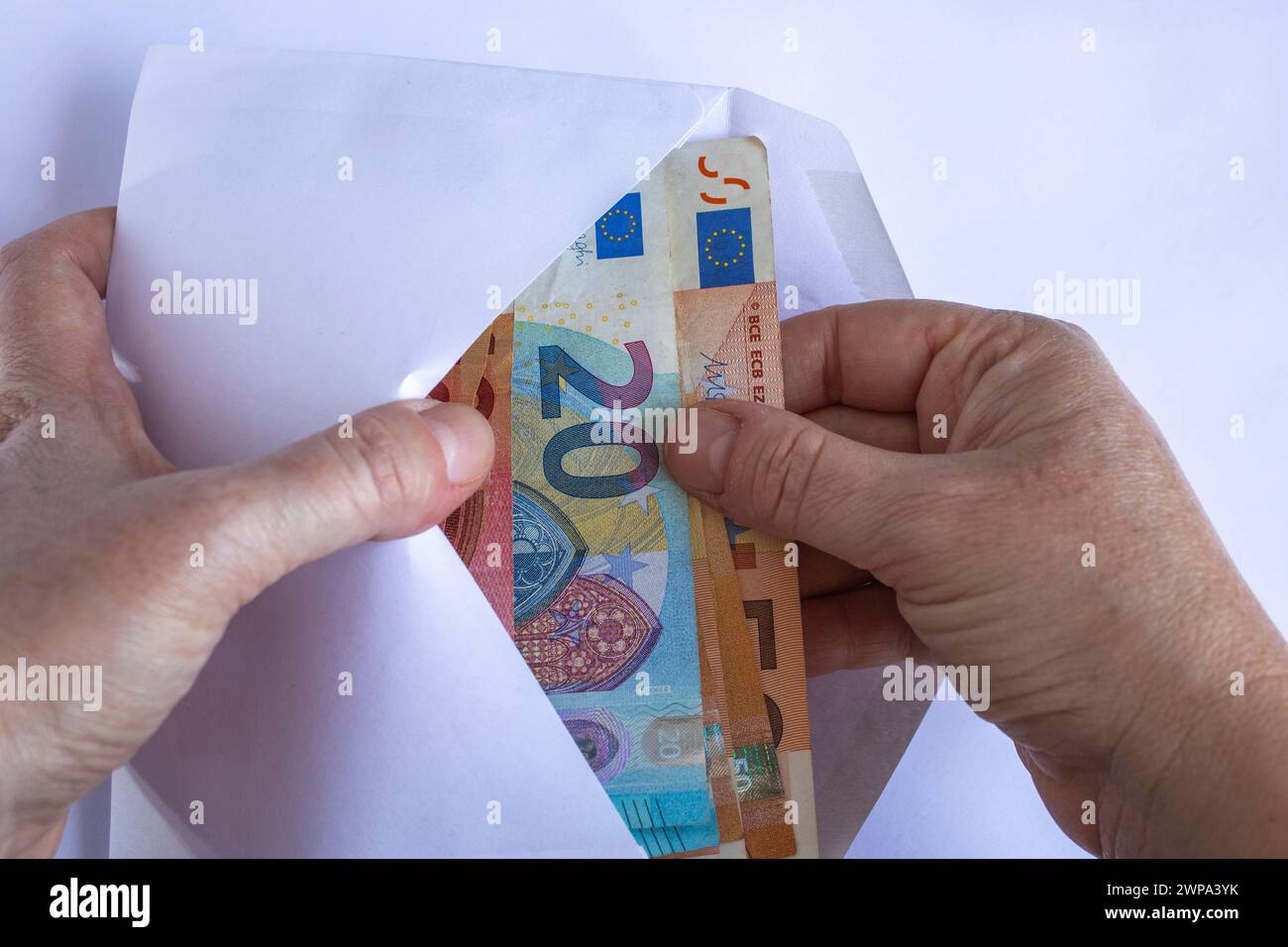 Die Hände der kaukasischen Frau nehmen 10-, 20- und 50-Euro-Scheine aus einem weißen Umschlag Stockfoto