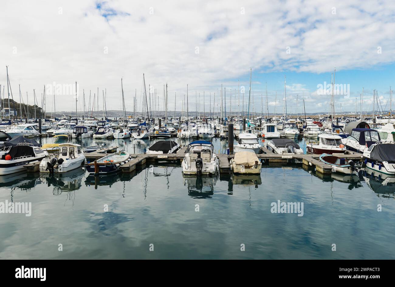 Brixham Marina und Hafen zeigen Boote vor Anker mit Fernsicht auf Torquay mit Reflexen von Booten im Wasser mit blauem Himmel Stockfoto