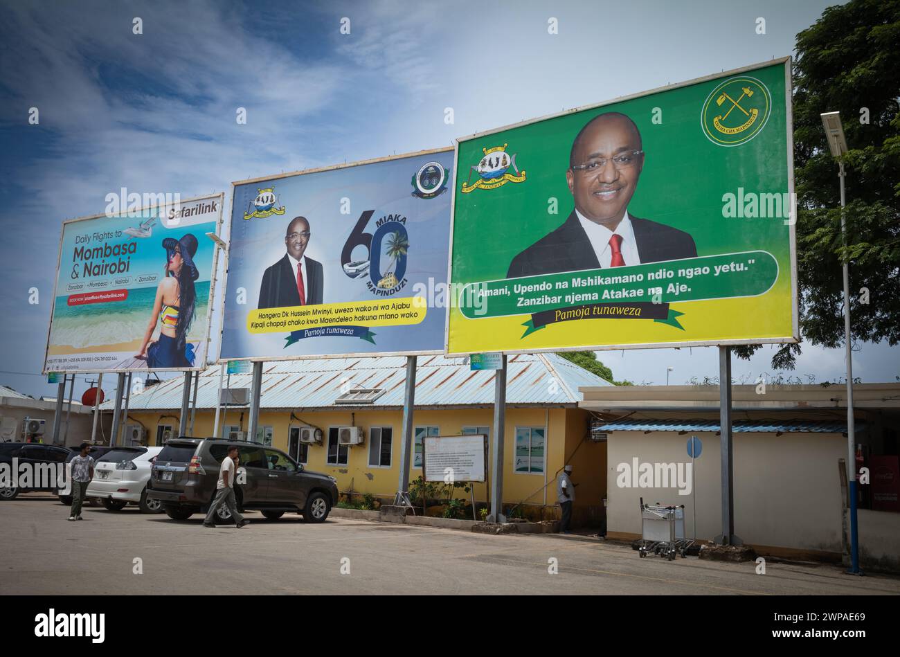 Politische Plakate für Hussein Mwinyi, den Präsidenten von Sansibar, und eine Reiseanzeige am Flughafen Sansibar, Tansania. Stockfoto