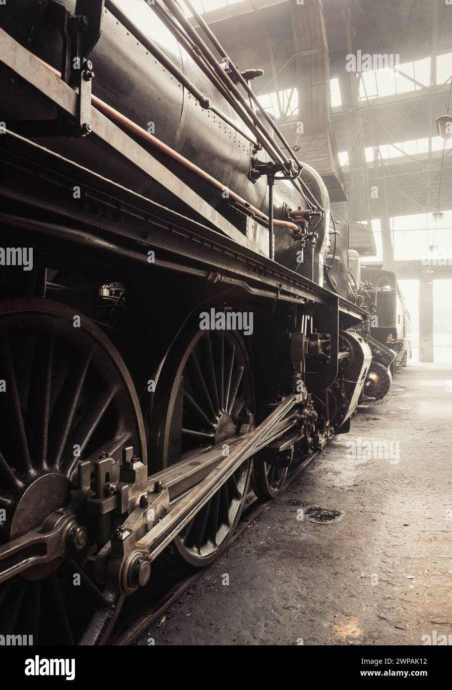 Steam Ära - alte Dampflokomotive im Zughaus. Dampflokomotive im Depot. Bild in warmen Tönen (fast Sepia). Der Innenraum des Depots ist mit Rauch gefüllt. Stockfoto