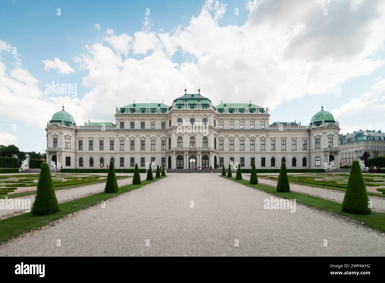 Oberer Belvedere-Palast - nördliche Seite. Gerader Pass führt zu einem 3-stöckigen Barockpalast aus dem 18. Jahrhundert an einem sonnigen Tag. Beigefarbener Palast mit Kupferdach. Stockfoto