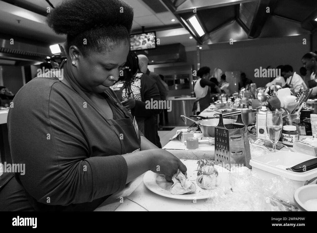 Eine Frau, die Essen mit einem Messer an einem Tisch schneidet Stockfoto