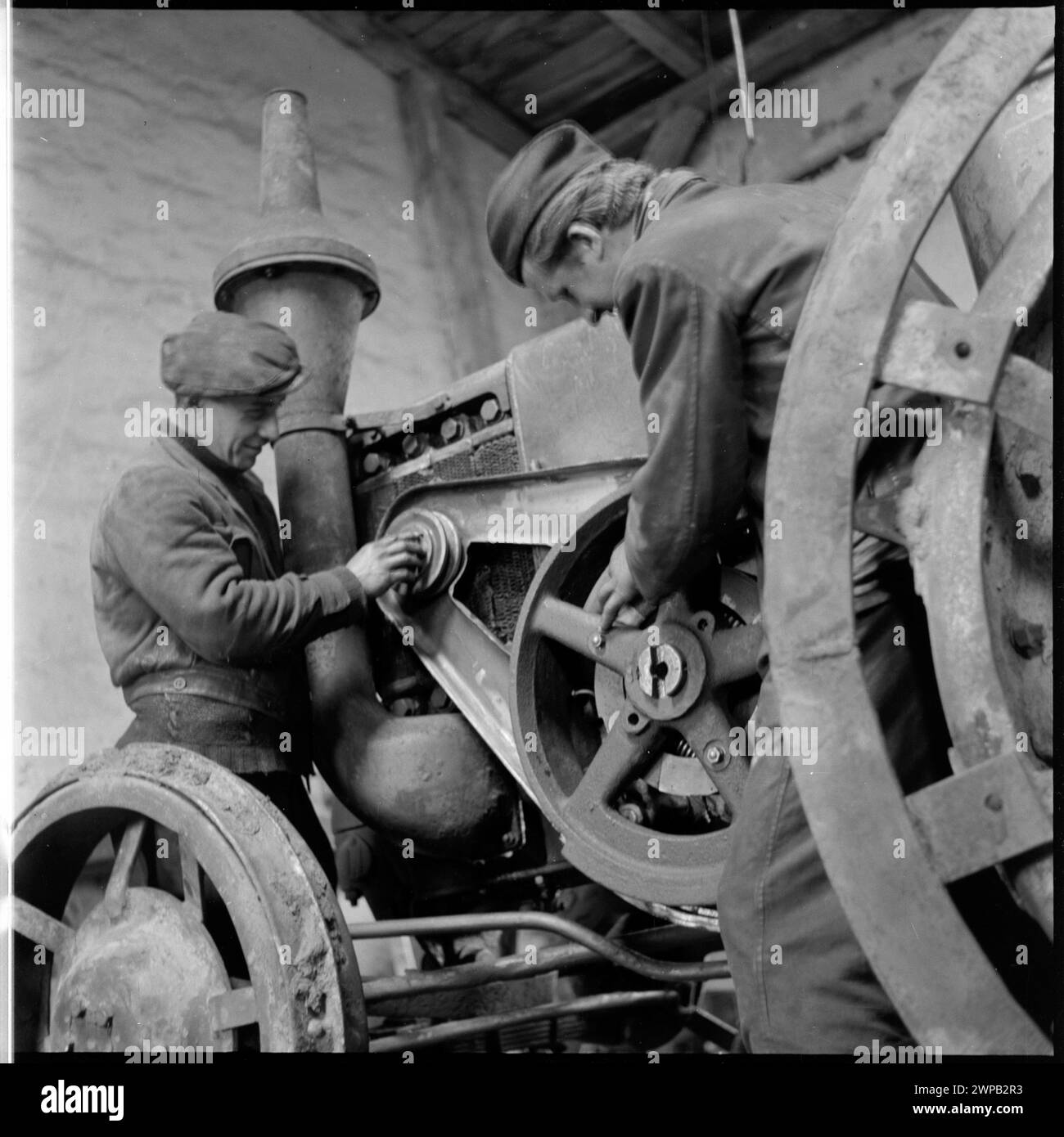 Mechaniker, die am ersten Ursus-Traktor der Nachkriegszeit bei der Staatsfeuerwehr in Karsk Pyrzycki arbeiten, aufgenommen in einer Fotoserie von Helena Adamczewska aus dem Jahr 1954. Stockfoto