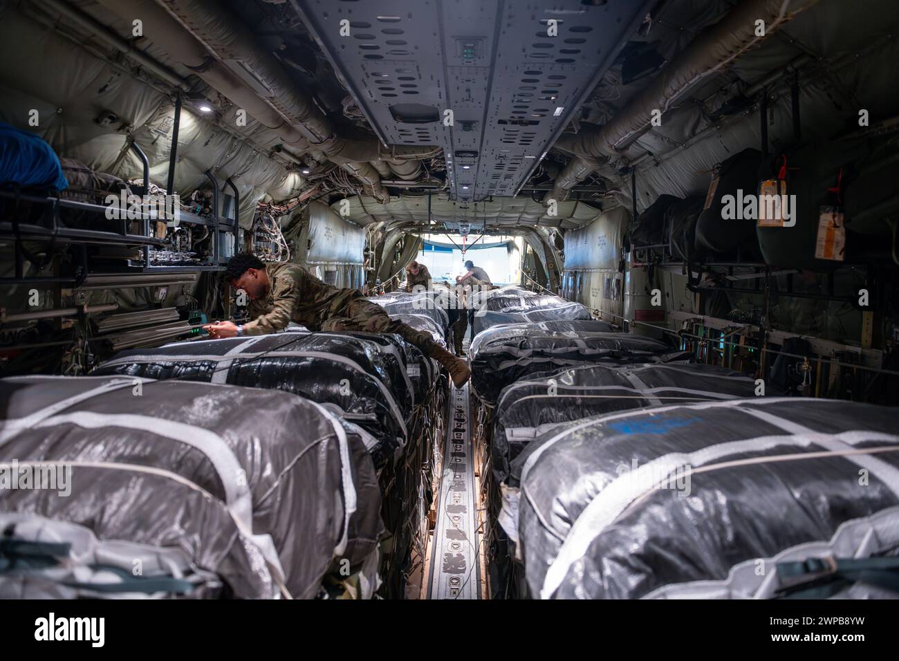 Azraq, Jordanien. März 2024. Ladungsträger der US-Luftwaffe und Armeegeräte überprüfen die Ausrüstung an einem Fallschirm, der an Paletten humanitärer Hilfe befestigt ist, in der Frachtbucht eines C-130J Super Hercules-Flugzeugs der US-Luftwaffe auf der Muwaffaq Salti Air Base, 5. März 2024 in Azraq, Zarqa Governorate, Jordanien. Die Nahrungsmittelhilfe wird an palästinensische Flüchtlinge abgegeben, die vom israelischen Krieg gegen die Hamas gefangen sind. Quelle: SRA Lauren Jacoby/US Airforce Photo/Alamy Live News Stockfoto