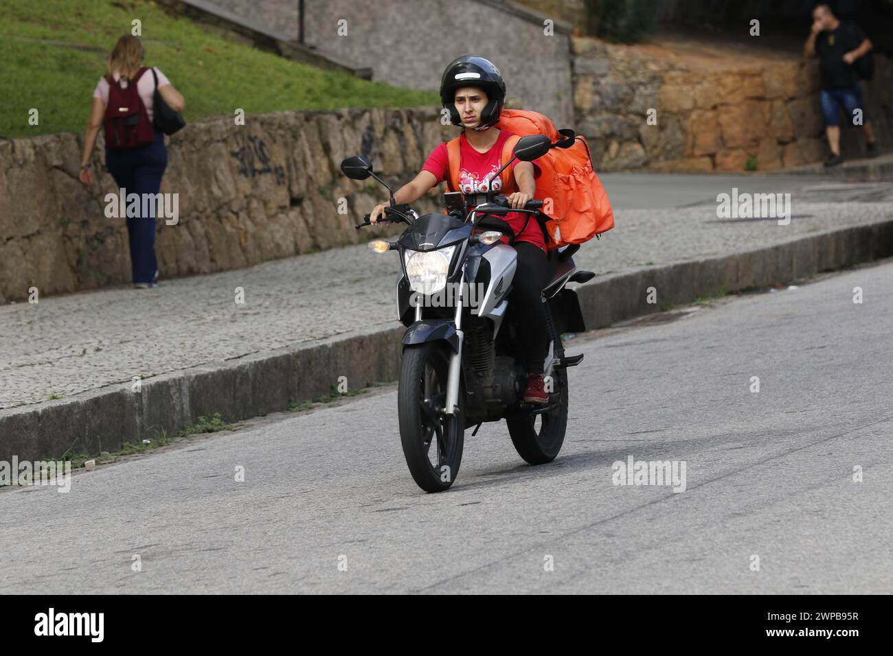 Lieferarbeiter. Lieferung von Lebensmitteln über den Mobile-App-Service. Tragetasche für Biker. Logistics App Job Stockfoto