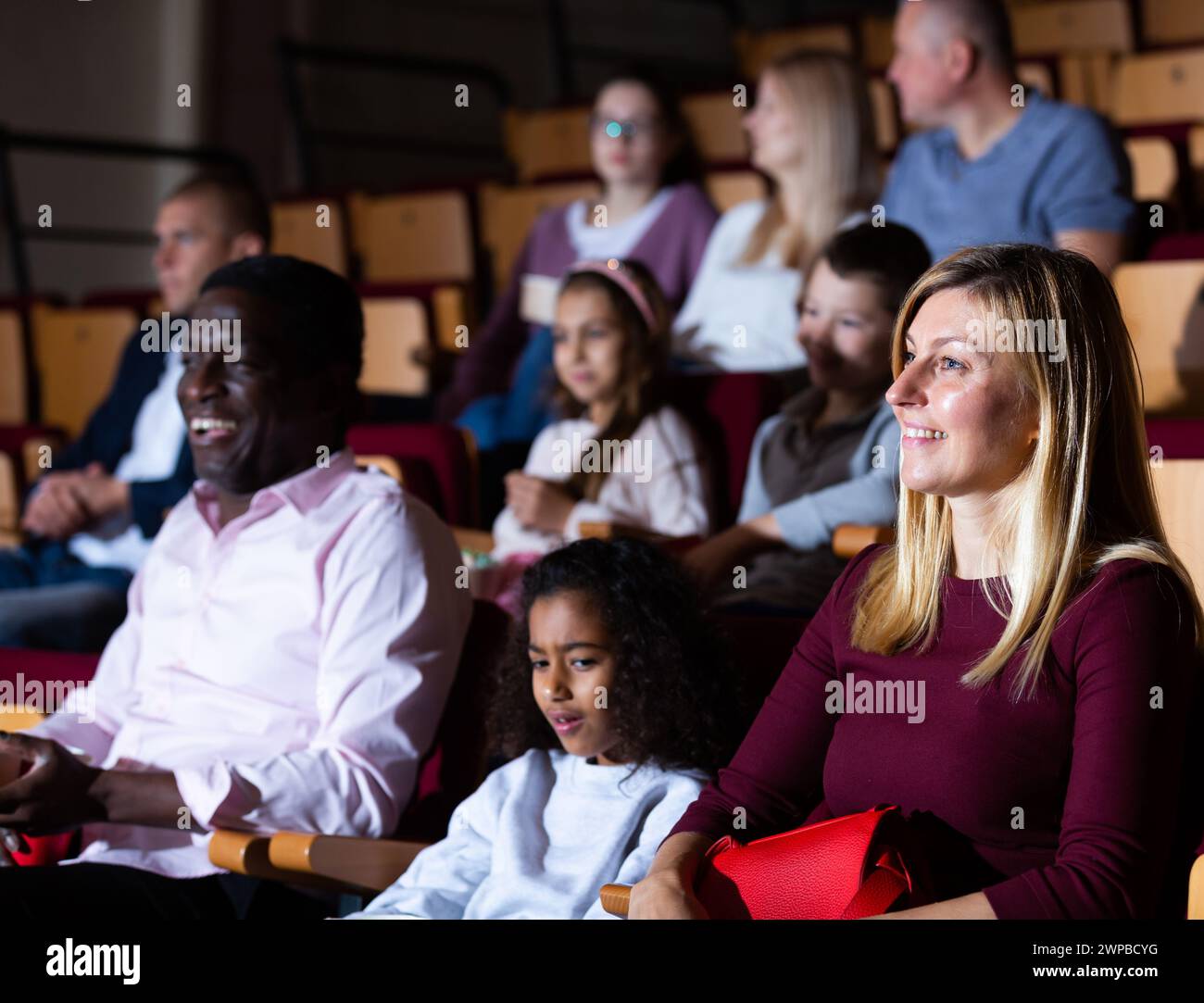 Internationale Familien essen Popcorn und sehen sich Comedy im Kinosaal an Stockfoto