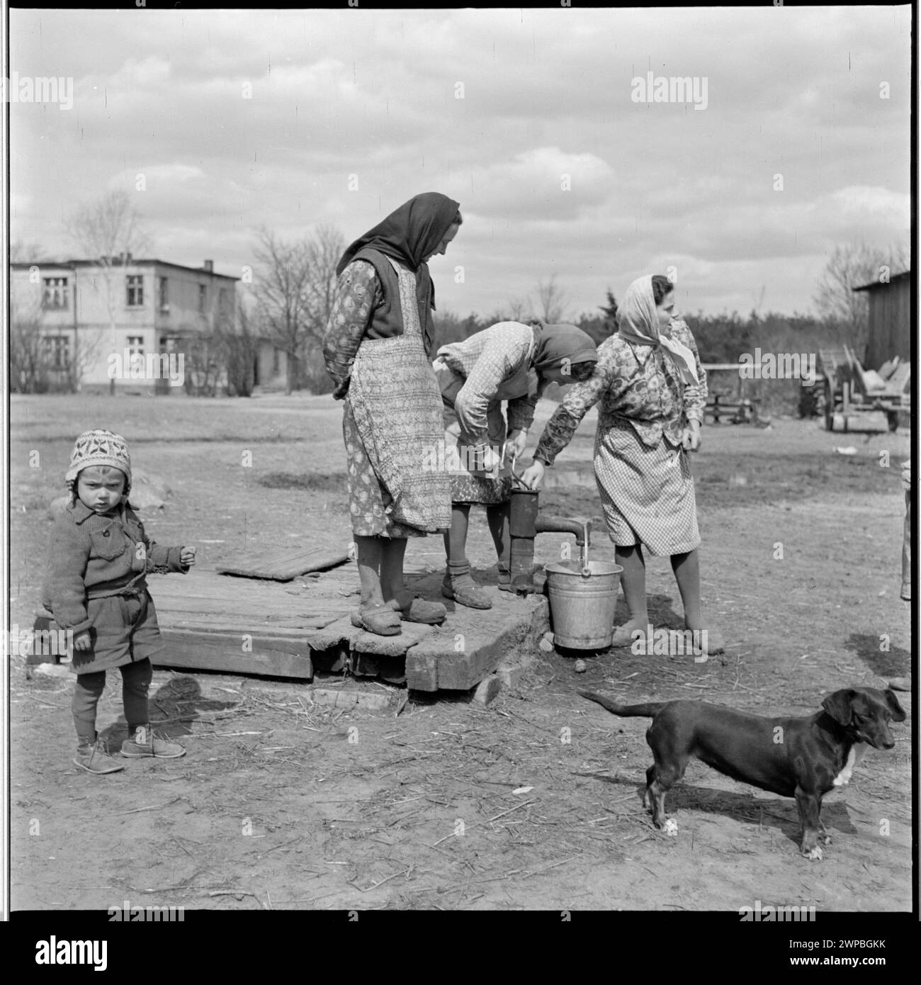 Foto von Frauen und einem Kind an einem Brunnen der PGR in Karsk Pyrzycki im Jahr 1954, das das tägliche Leben in Polen der Nachkriegszeit veranschaulicht. Stockfoto