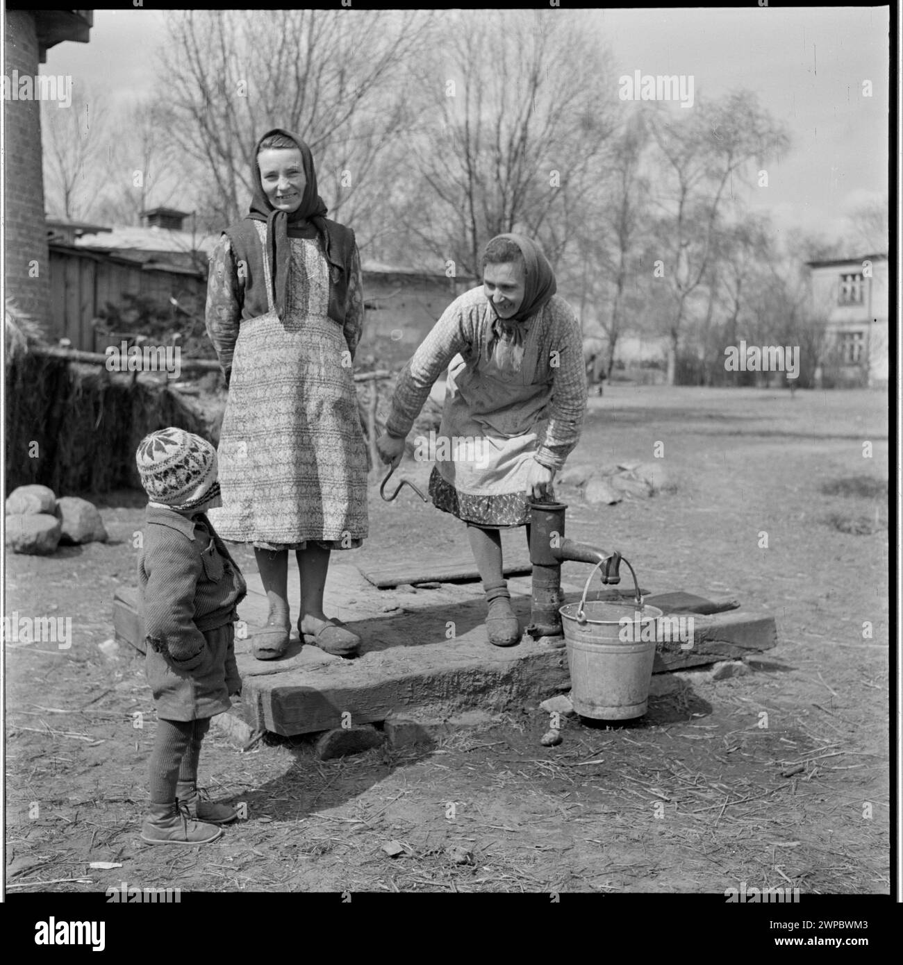 Foto von Frauen und einem Kind an einem Brunnen der PGR in Karsk Pyrzycki im Jahr 1954, das das tägliche Leben in Polen der Nachkriegszeit veranschaulicht. Stockfoto
