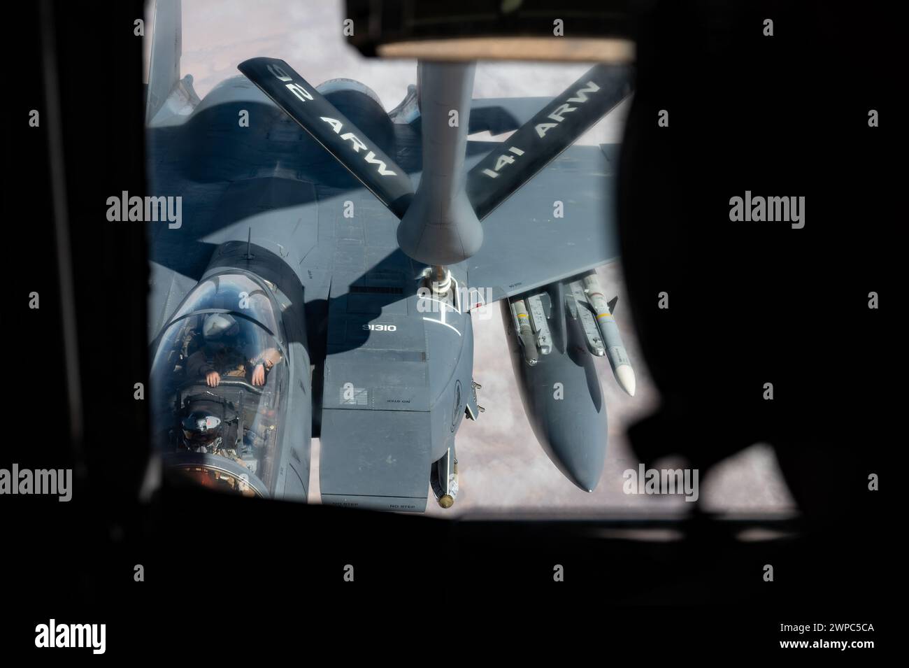 Ein Luftwaffenbetreiber betankt in einem KC-135 Stratotanker einen F-15E Strike Eagle an einem unbekannten Ort Stockfoto