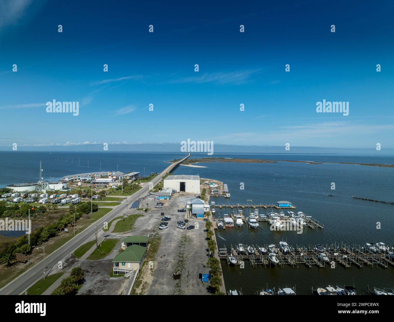 Blick aus der Vogelperspektive auf Dauphin Island Verbindungsbrücke und Marina mit luxuriösen Strandhäusern und Segelbooten Stockfoto