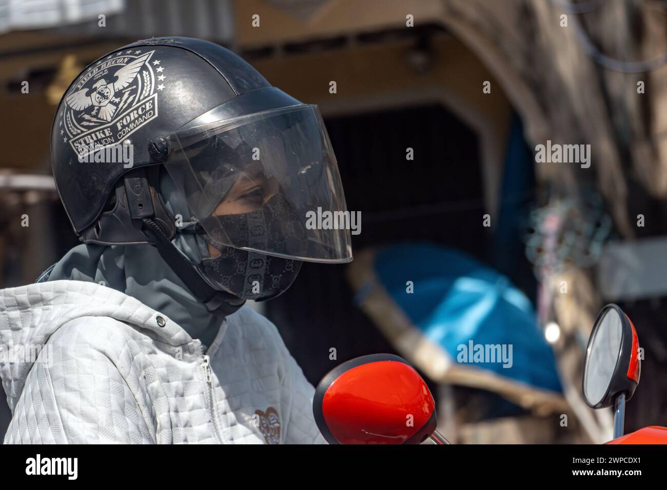 YALA, THAILAND, 1. März 2024, Eine Frau fährt ein Motorrad in einem Helm mit einem Abdruck Stockfoto