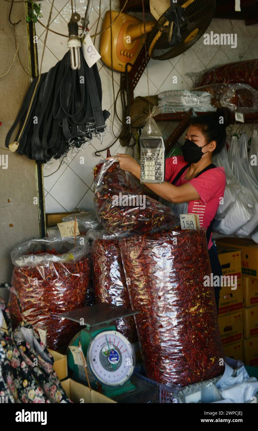 Eine Thailändin, die in einem kleinen Gewürzladen auf der Maha Rat Rd in Bangkok, Thailand, Taschen mit roten Chilis packt. Stockfoto