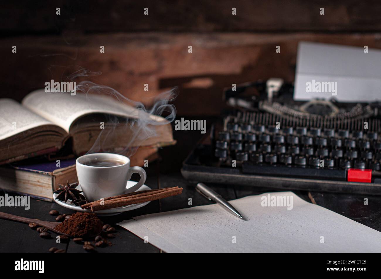 Foto eines Buches, einer Tasse Kaffee und einer Schreibmaschine auf einem Schreibtisch Stockfoto