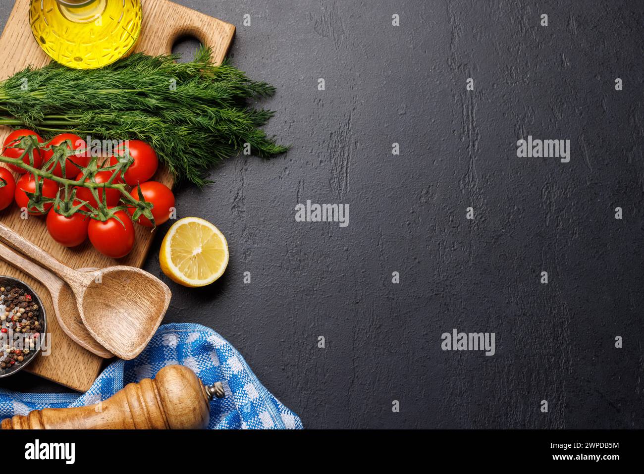 Kochszene: Kirschtomaten, Kräuter und Gewürze auf dem Tisch. Flache Ladefläche mit Kopierraum Stockfoto