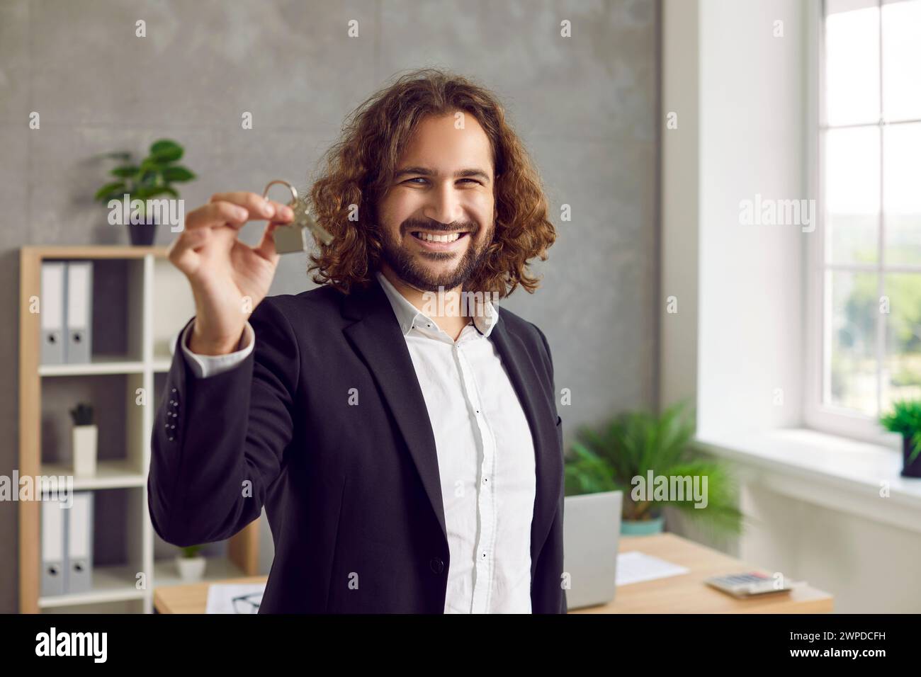 Porträt eines jungen glücklichen, attraktiven Mannes mit Hausschlüsseln in der Hand. Stockfoto