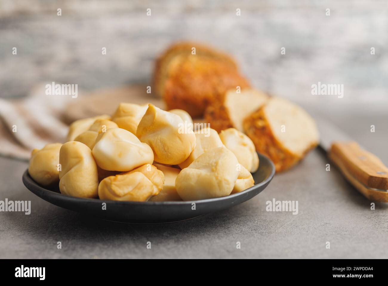 Geräucherter Mini-Scamorza-Käse. Traditioneller italienischer Käse auf dem Teller auf dem Küchentisch. Stockfoto