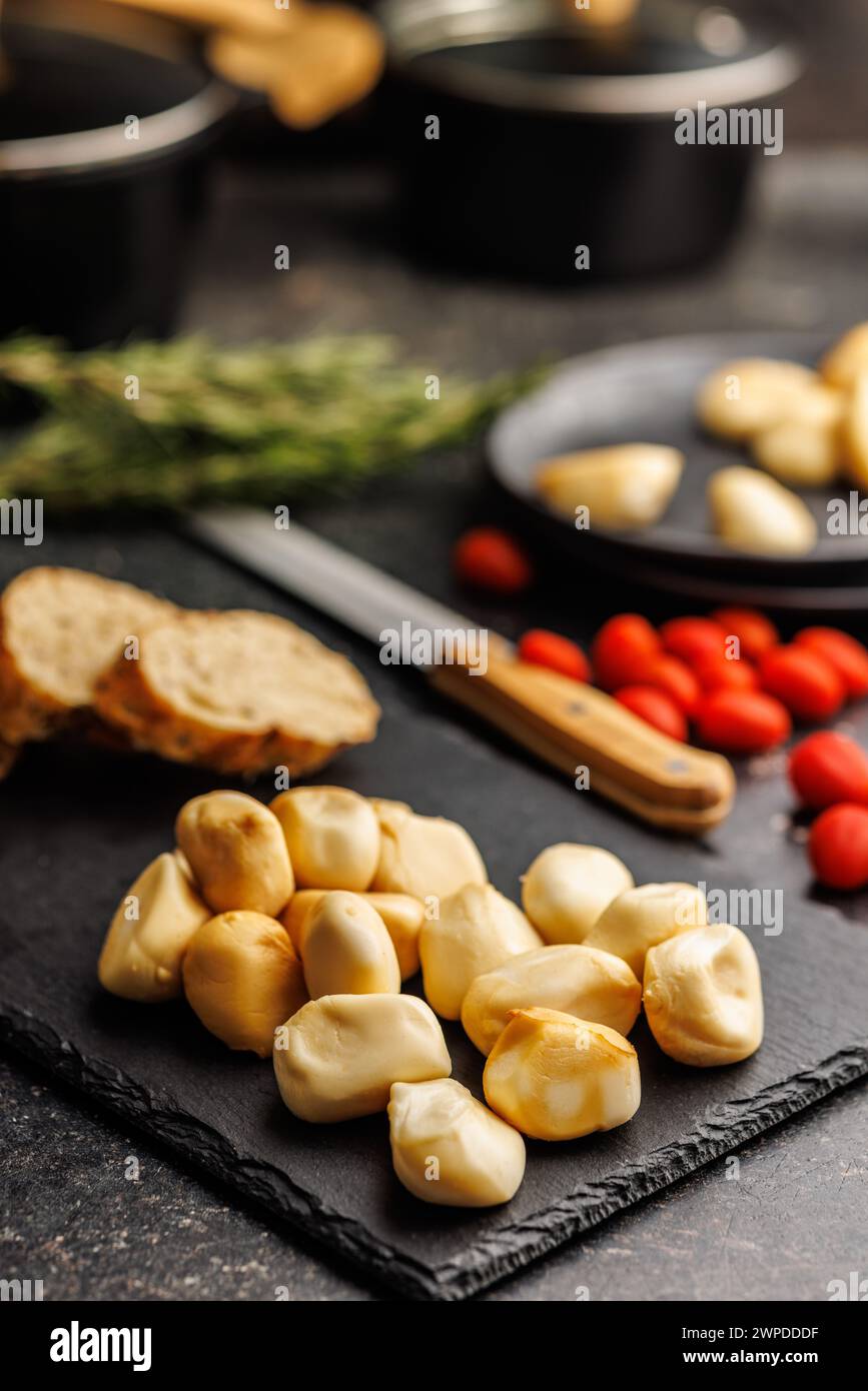 Geräucherter Mini-Scamorza-Käse. Traditioneller italienischer Käse auf Schneidebrett auf dem schwarzen Tisch. Stockfoto