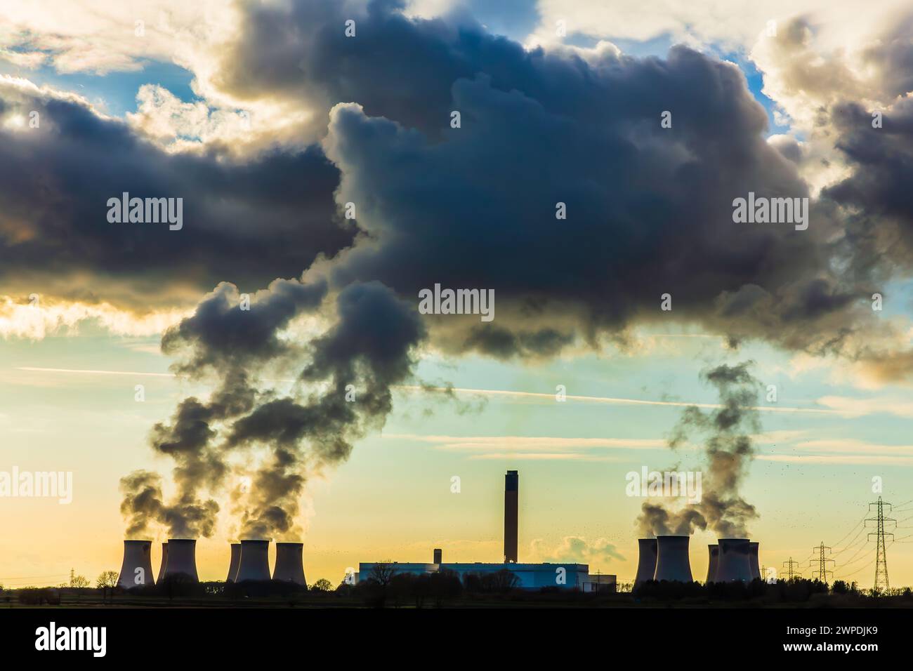 Sonnenuntergang über Drax Power mit Hunderten von Staren, die um die Kühltürme fliegen und aufsteigenden Wasserdampf auf eine riesige Wolkenformation trifft. Horizontal Stockfoto