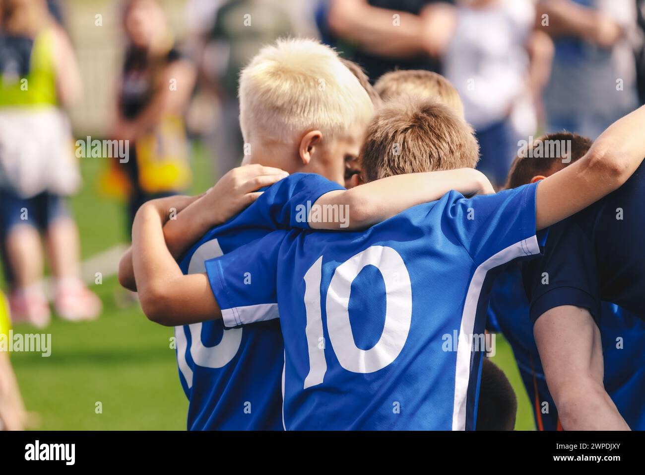 Kinder im Sportteam. Freunde in einer Fußballmannschaft. Männliche Fußballspieler, die sich vor einem Spiel in einem Kreis zusammenscharen Stockfoto