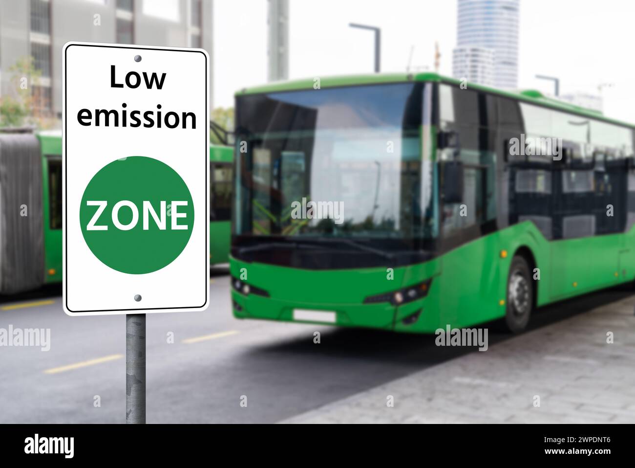 Straßenschild für die EMISSIONSZONE auf einem Hintergrund grüner Elektrobusse. Sauberes Mobilitätskonzept Stockfoto