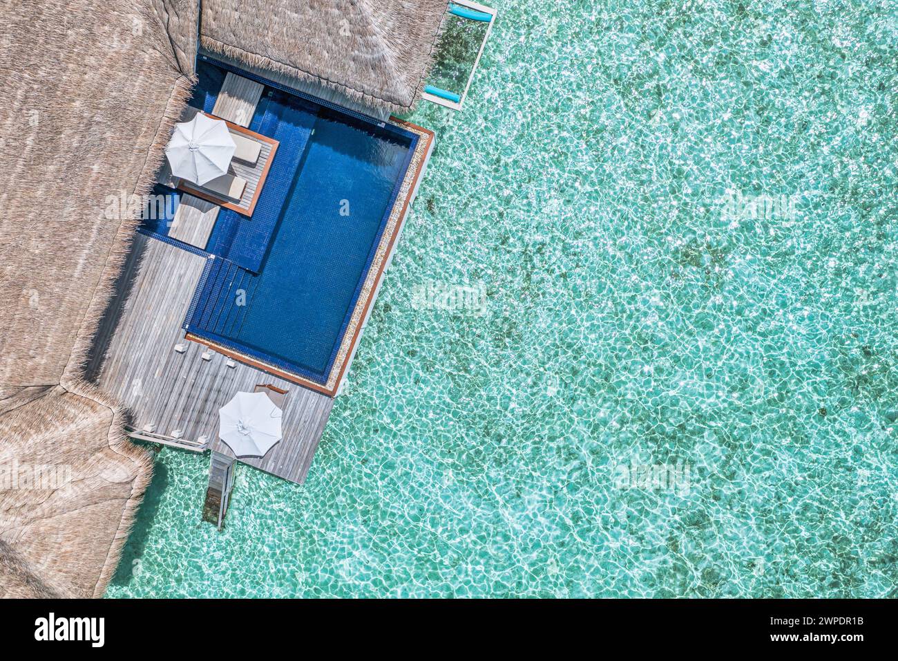 Strandresort aus der Luft. Minimalistischer Infinity-Pool mit Blick auf den Strand und der blauen Lagune mit wunderschönen Wellen und Wellen. Luxusreisen Stockfoto