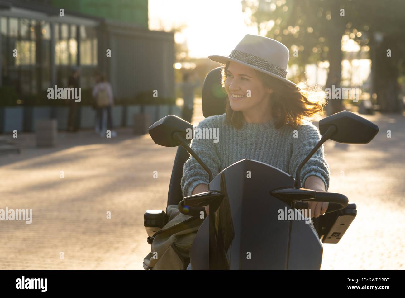 Frau, die auf einer Straße in der Stadt einen Elektroroller mit vier Rädern fährt. Stockfoto
