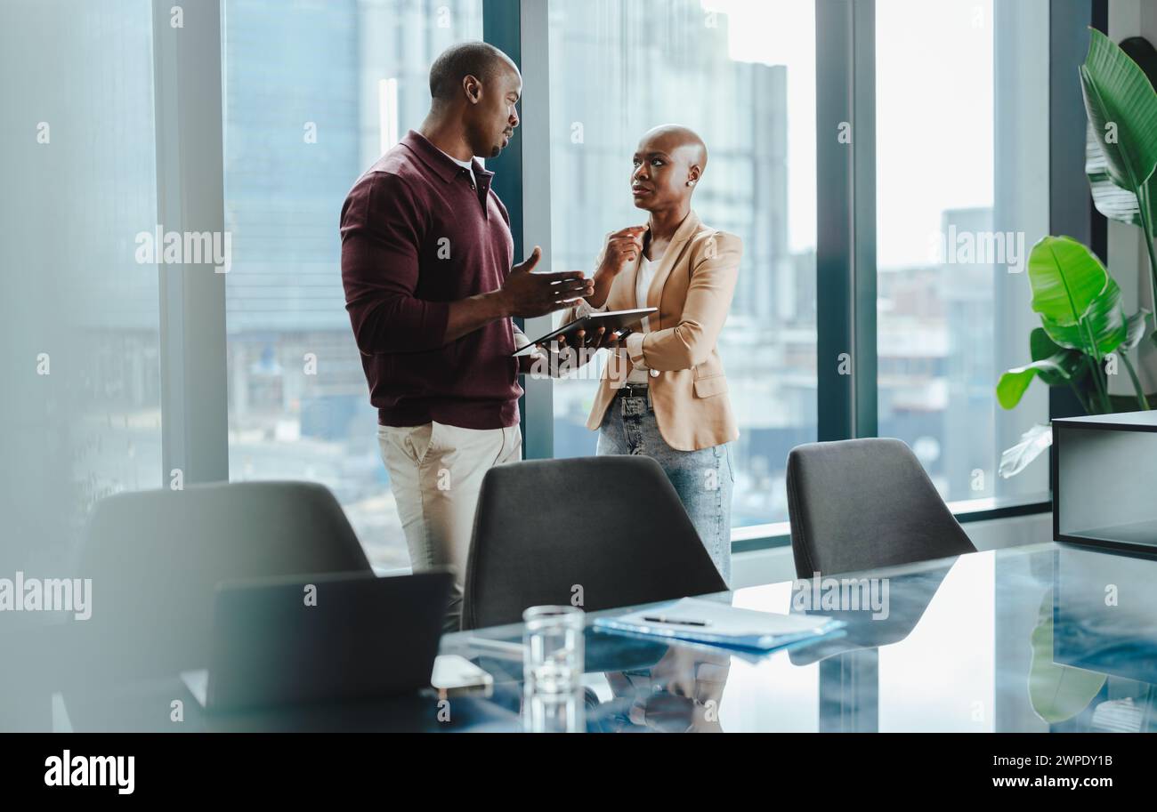 Zwei Fachleute stehen zusammen in einem Sitzungssaal, diskutieren Geschäfte und planen Geschäftsabschlüsse. Teamwork, Technologie und Erfolg sind offensichtlich als Stockfoto