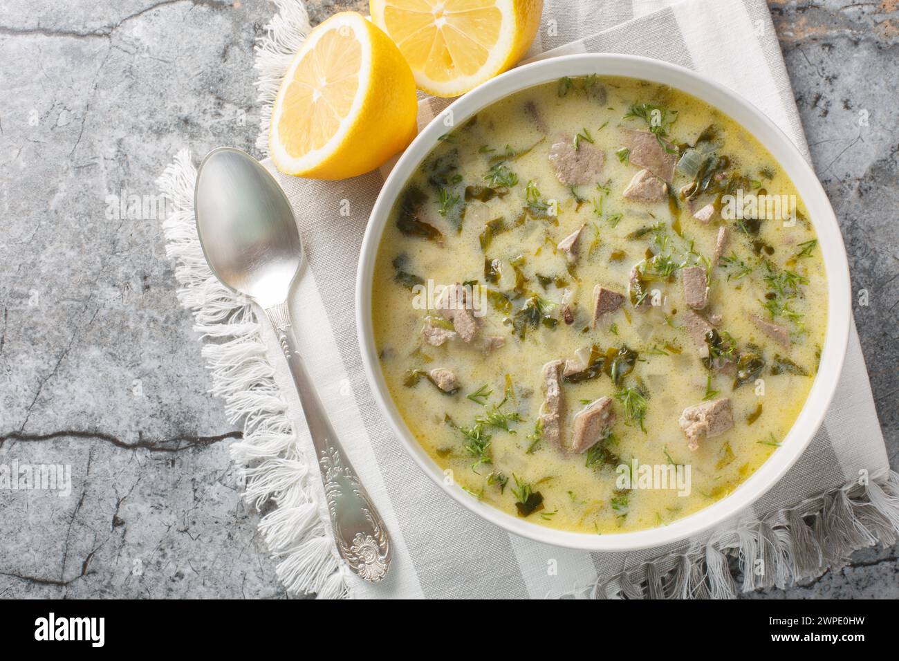 Magiritsa griechische Ostersuppe mit Lammdarm und Leber, Kräutern, mit Ei und Zitronensauce in einer Schüssel auf einem Marmortisch. Horizontal Stockfoto