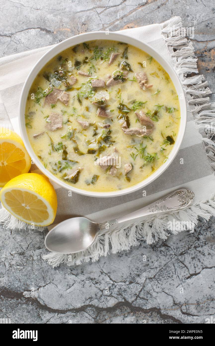 Klassische Magiritsa-Suppe mit Lammfleisch, Schlachtnebenerzeugnissen und Gemüse in einer Schüssel auf einem Marmortisch. Vertikale Draufsicht von oben Stockfoto