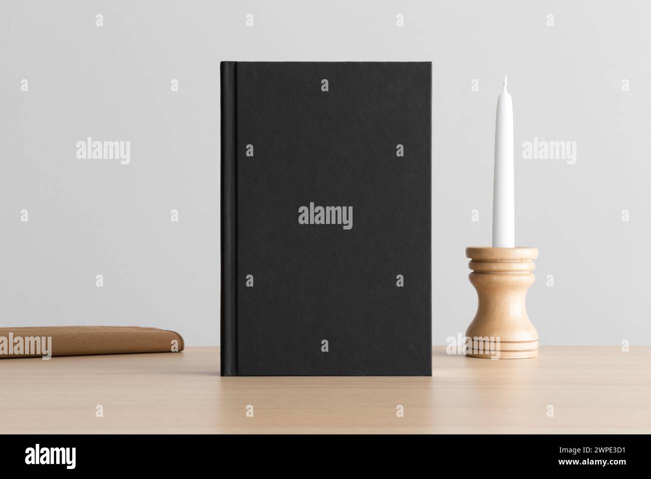 Schwarzes Buchmockup mit Kerzendekoration und Buch auf dem Holztisch. Stockfoto