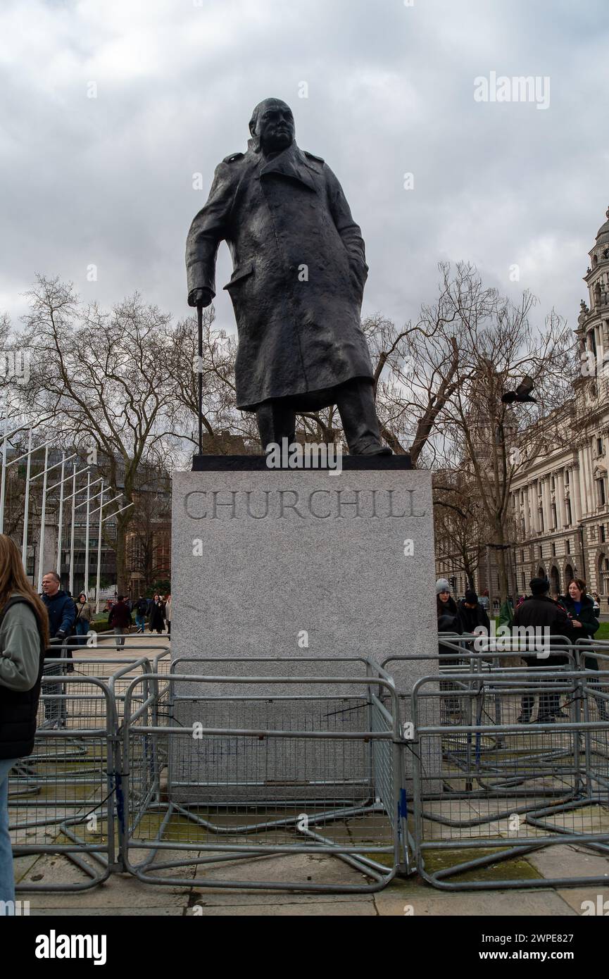 Westminster, London, Großbritannien. März 2024. Die berühmte Statue von Sir Winston Churchill gegenüber Big Ben und dem House of Commons in Westminster, London, hat Barrieren, um es den Demonstranten zu erschweren, auf die Statue zu klettern oder sie zu entlarven, wie es zuvor geschehen ist. Der Police Crime, Sentencing and Courts Act 2022 und der Public Order Act 2023 enthalten neue Straftaten der „strafrechtlichen Beschädigung von Denkmälern und Statuen“, die neue Gesetzgebung macht es jedoch nicht zu einem Verbrechen, auf Denkmäler zu klettern. Kredit: Maureen McLean/Alamy Stockfoto