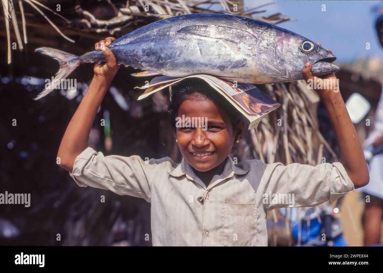 Sri Lanka, Negombo, Mädchen bringt einen Thunfisch vom Fischmarkt nach Hause. Stockfoto