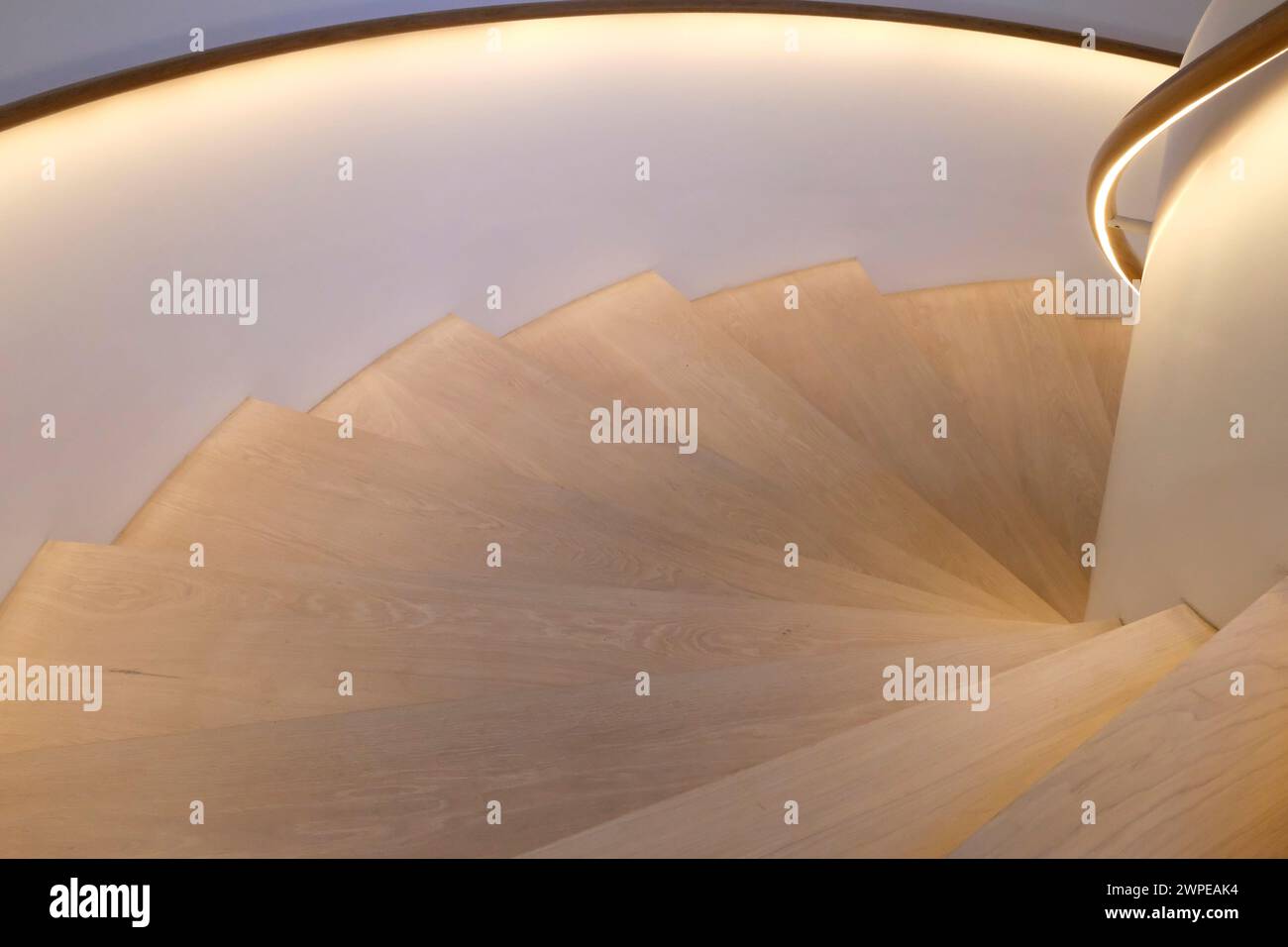 Holztreppe nach unten mit beleuchteten Handläufen Stockfoto