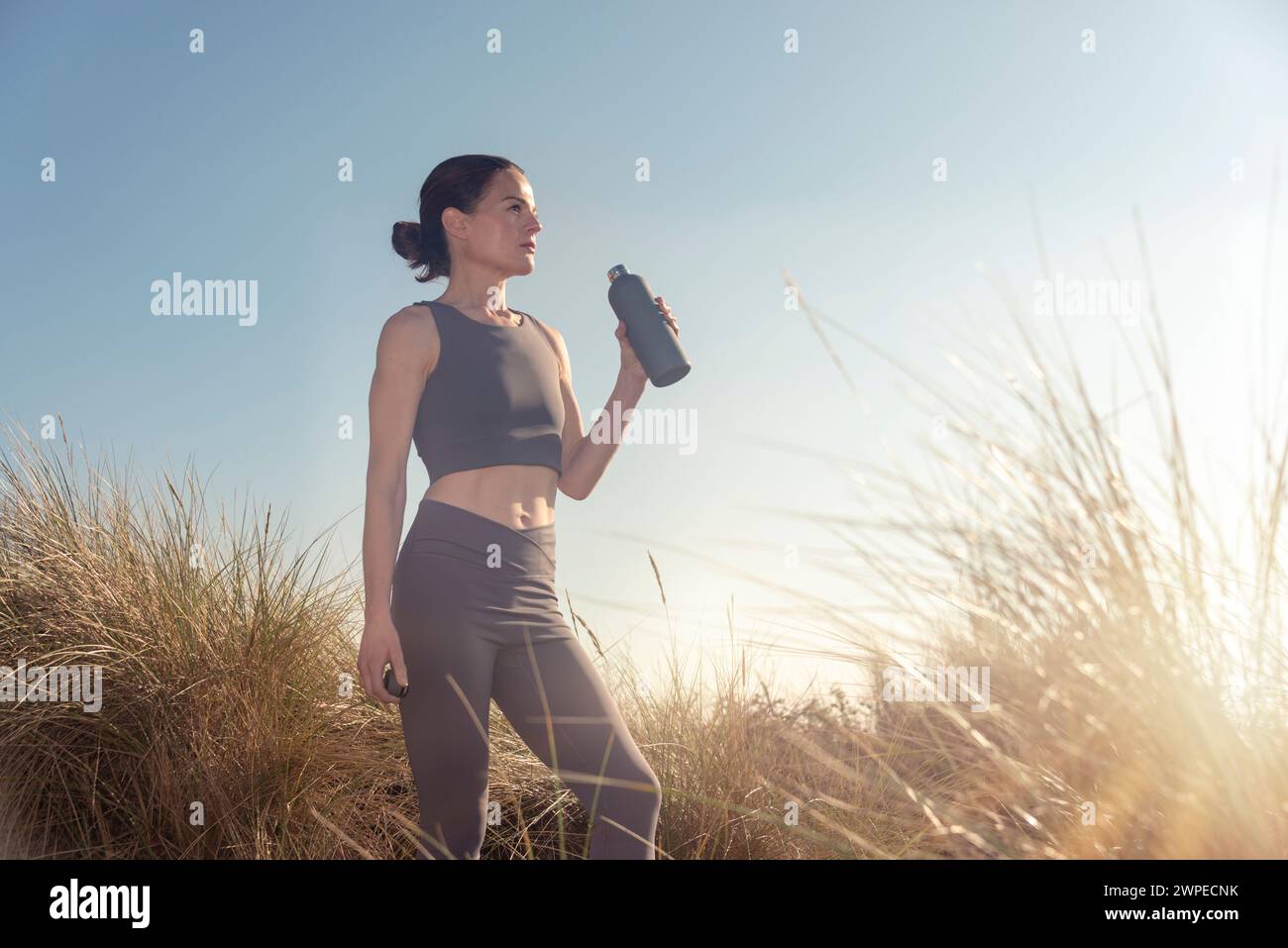 Sportliche Läuferin, die eine Wasserflasche hält Stockfoto