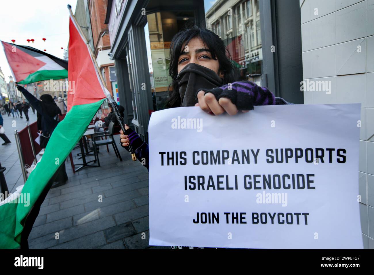 Ein Demonstrant steht vor Pret A Krippe mit einer palästinensischen Flagge und einem Plakat mit der Aufschrift "diese Kompanie unterstützt den israelischen Völkermord, tritt dem Boykott bei" während einer Demonstration. Demonstranten fordern, dass die Leute Costa Coffee boykottieren. Ihre Muttergesellschaft Coca-Cola betreibt eine Fabrik in der illegalen israelischen Siedlung Atarot in dem Gebiet, das von den Demonstranten als Palästina besetzt angesehen wird. Die Boykott Divestment and Sanctions (BDS)-Bewegung arbeitet daran, die internationale Unterstützung für Israels Unterdrückung der Palästinenser zu beenden und Israel unter Druck zu setzen, sich an das Völkerrecht zu halten, und hat eine Liste von Unternehmen zusammengestellt Stockfoto