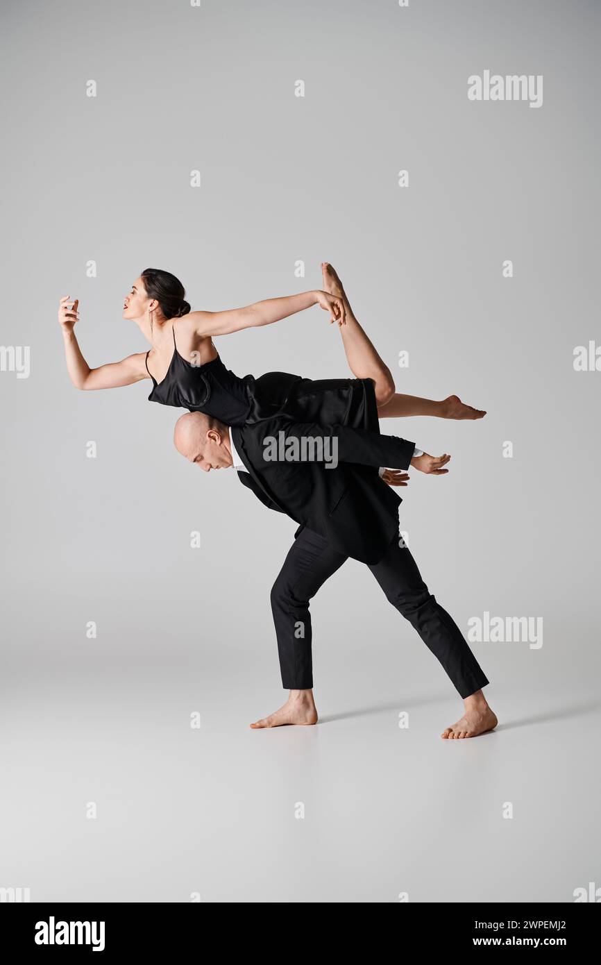 Barfuß junge Frau in schwarzem Kleid, die anmutig während der Tanzaufführung mit dem Mann balanciert Stockfoto