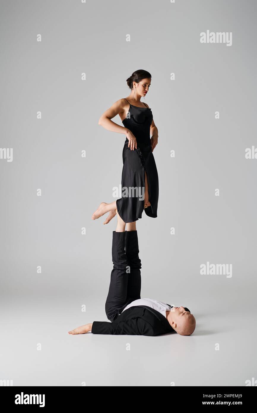 Athletisches Duo, ein paar Akrobaten, die Balance in einem Studio mit grauem Hintergrund spielen Stockfoto