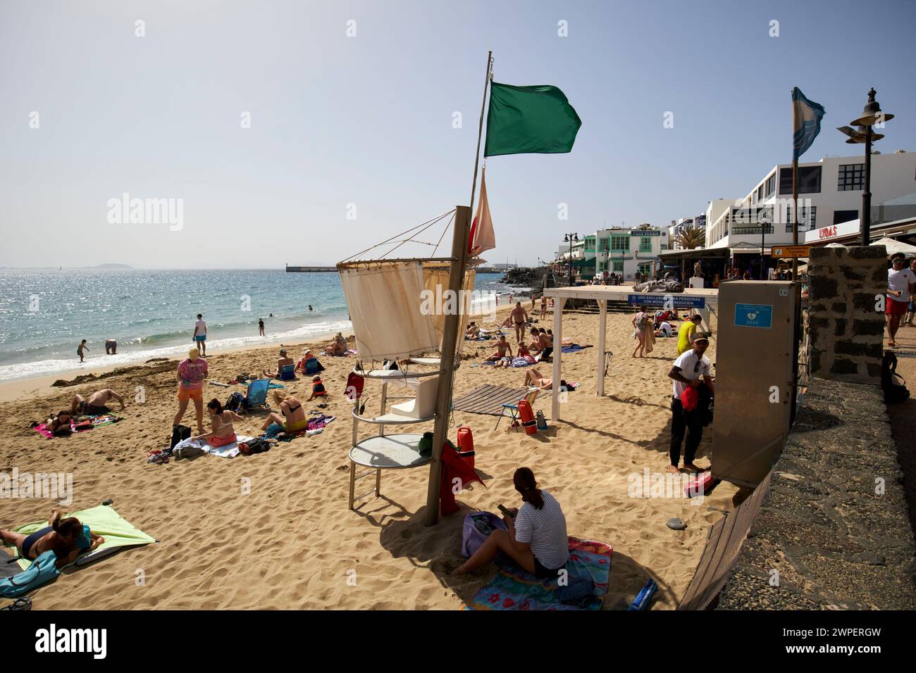 Die grüne Flagge ist sicher zum Schwimmen mit Rettungsschwimmer am beliebten Wintersonnenziel playa blanca Beach, Lanzarote, Kanarischen Inseln, spanien Stockfoto