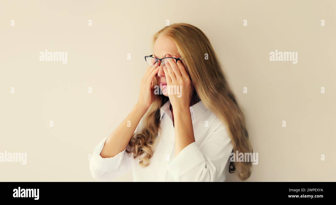 Müde überarbeitete Frau, die sich nach der Arbeit am Computer die Augen reibt und unter Augenanstrengung, trockenem Auge oder Kopfschmerzen leidet Stockfoto