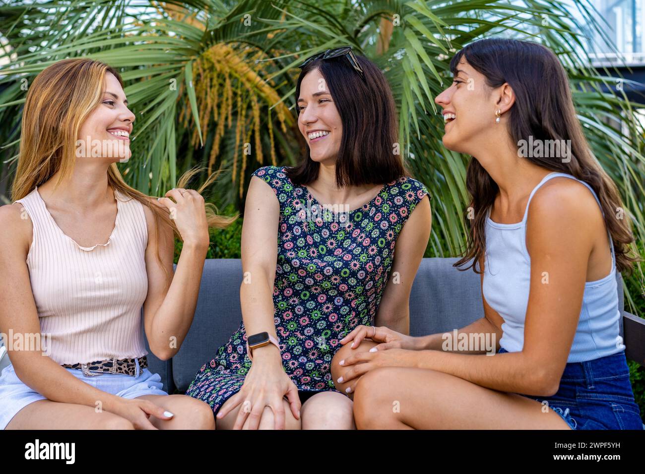 Drei schöne junge Frauen, die auf einer Couch plaudern Stockfoto