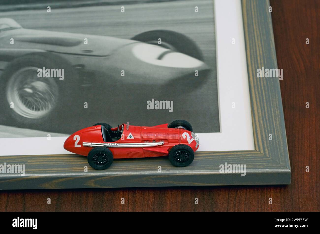 Altmodischer roter Spielzeugrennwagen (alfetta gp159) und gerahmtes Foto desselben Autos Stockfoto